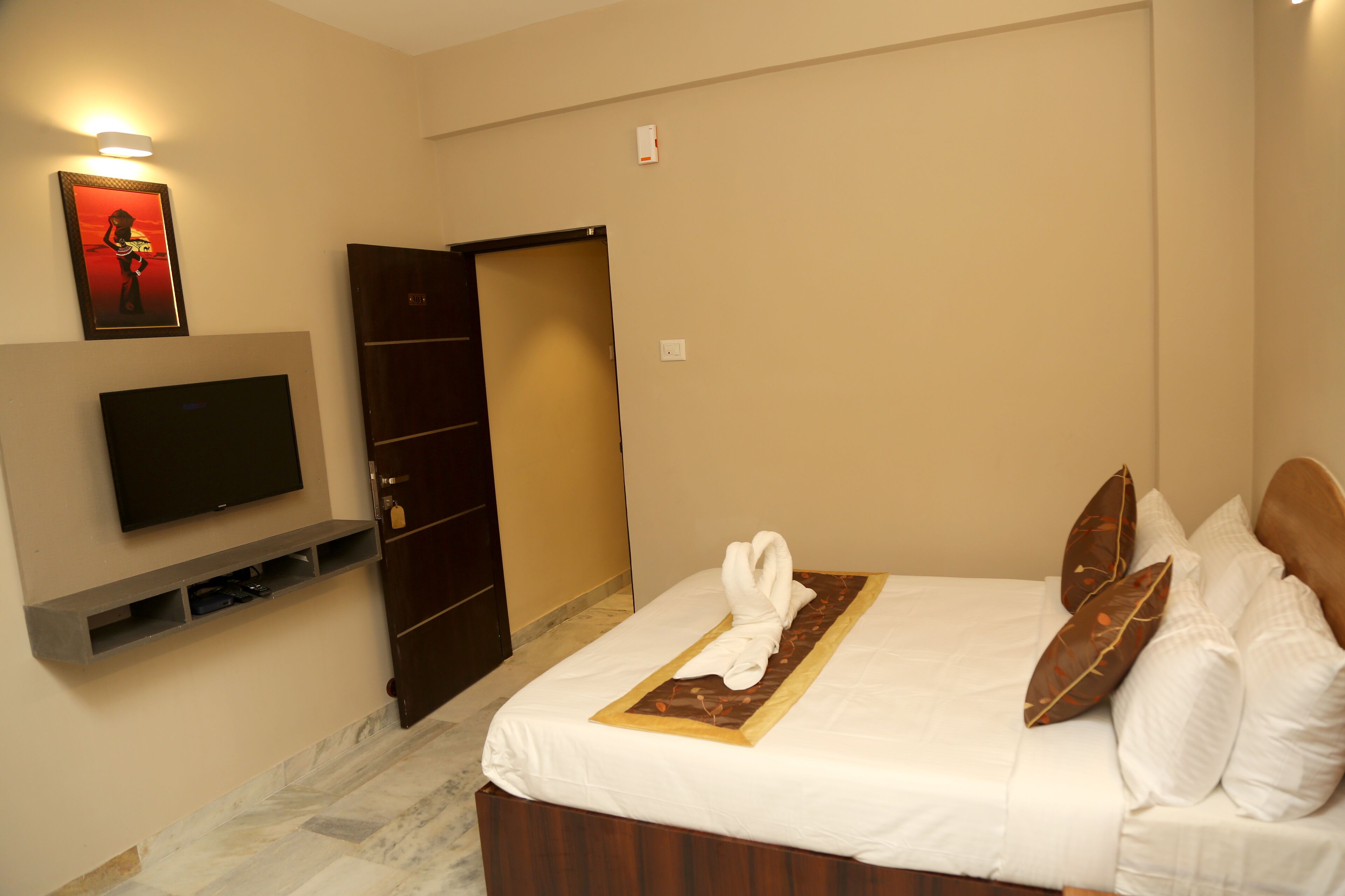 Ein Hotelzimmer mit Bett, Fernseher, Kleiderschrank und Tür.