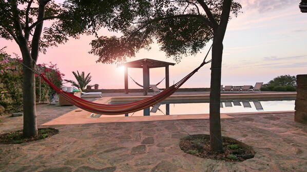 Een buitenzwembad, parasols bij het zwembad en ligstoelen