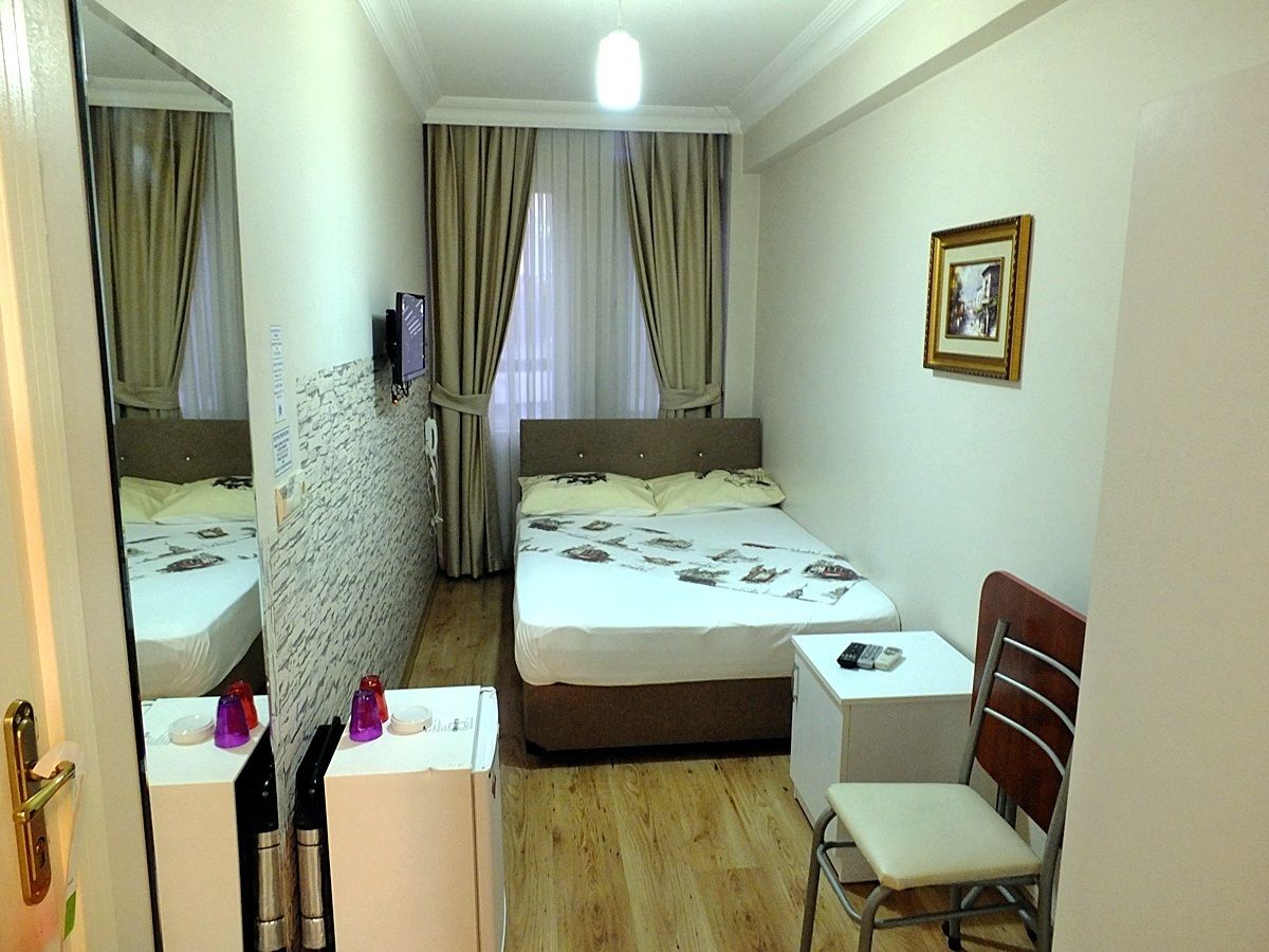 A hotel room with a bed, a desk, a chair, a mirror, and a picture on the wall.