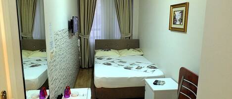 A hotel room with a bed, a desk, a chair, a mirror, and a picture on the wall.
