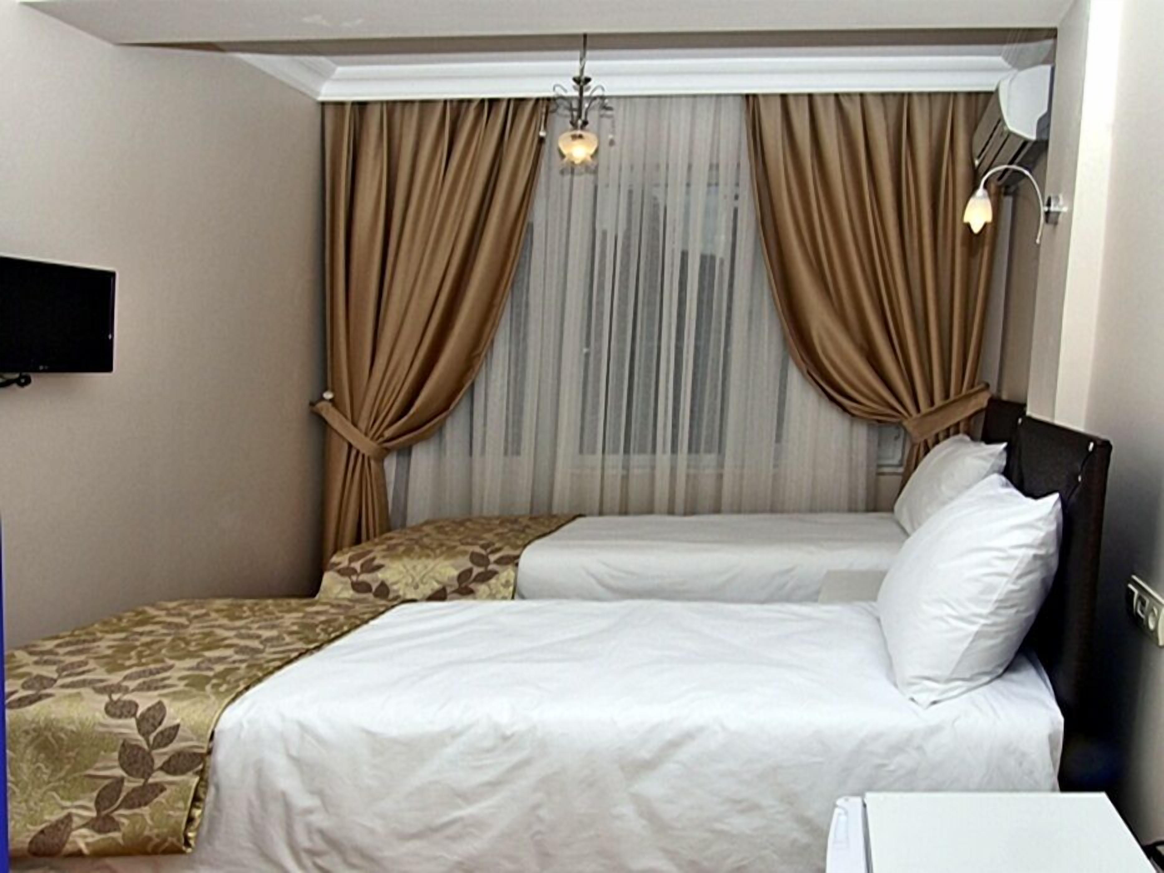 A hotel room with a bed, a bedside table, a lamp, and a TV on the wall.