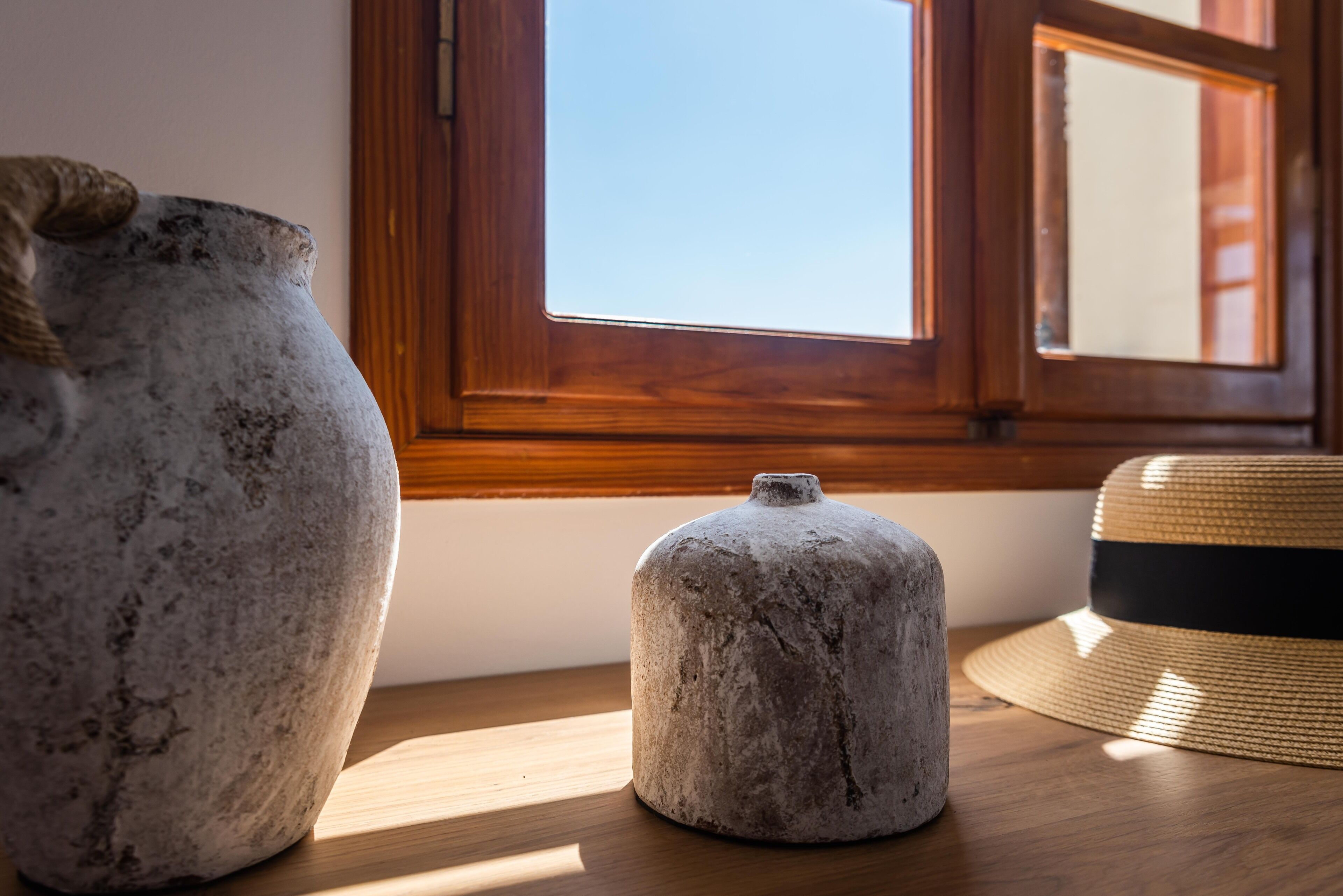 Dos recipientes de piedra sobre una mesa de madera cerca de una ventana.