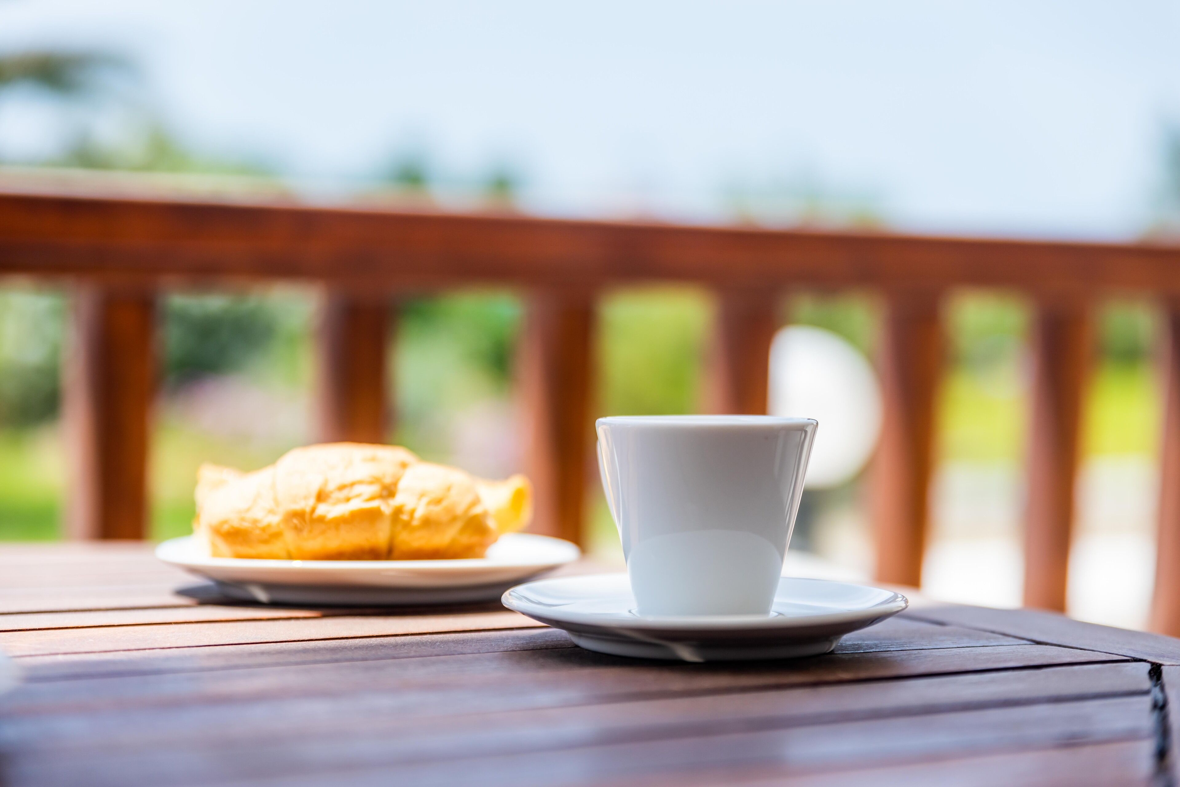 A table with a white cup and a plate of food.