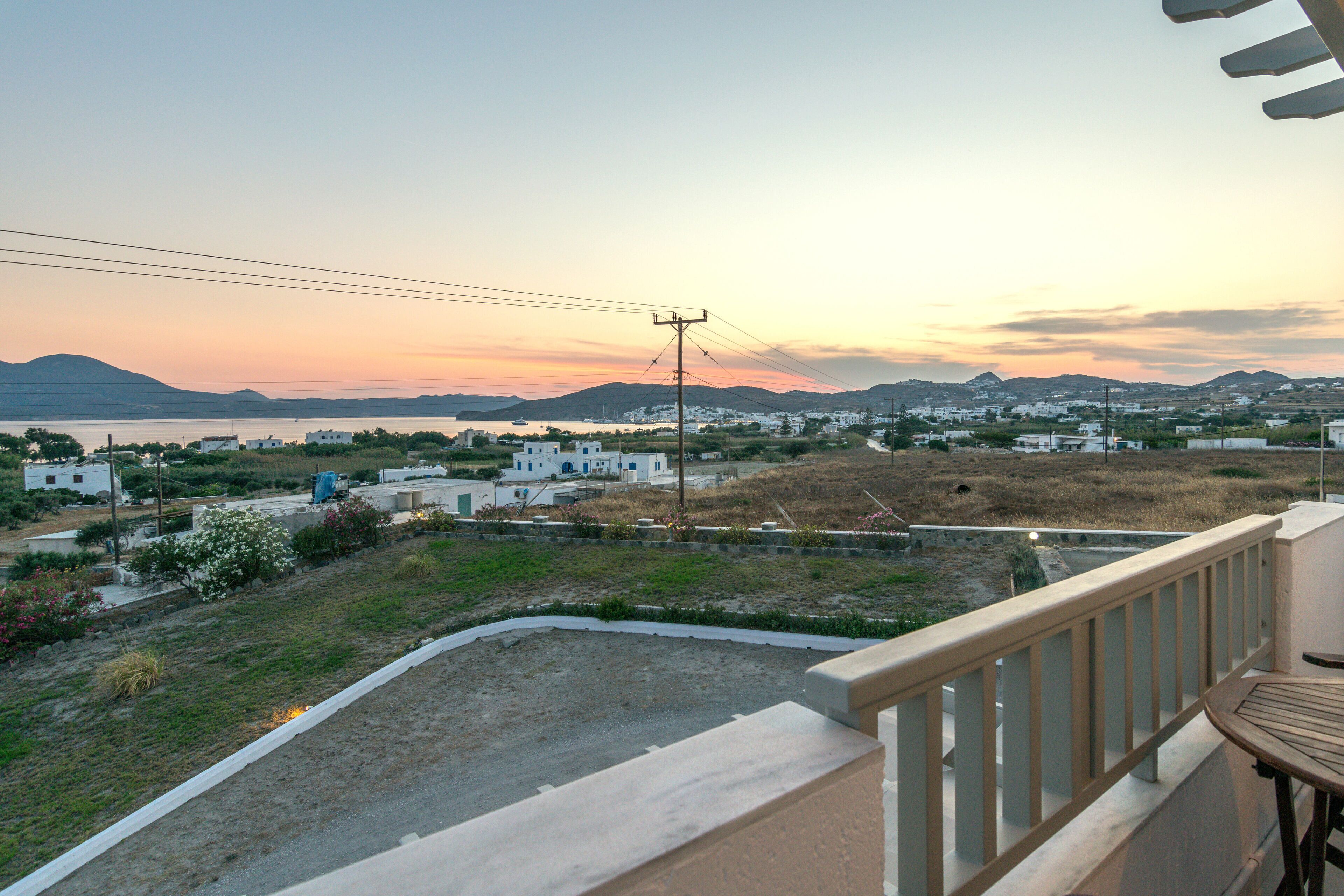 Un balcón con vista a un pueblo costero al atardecer.