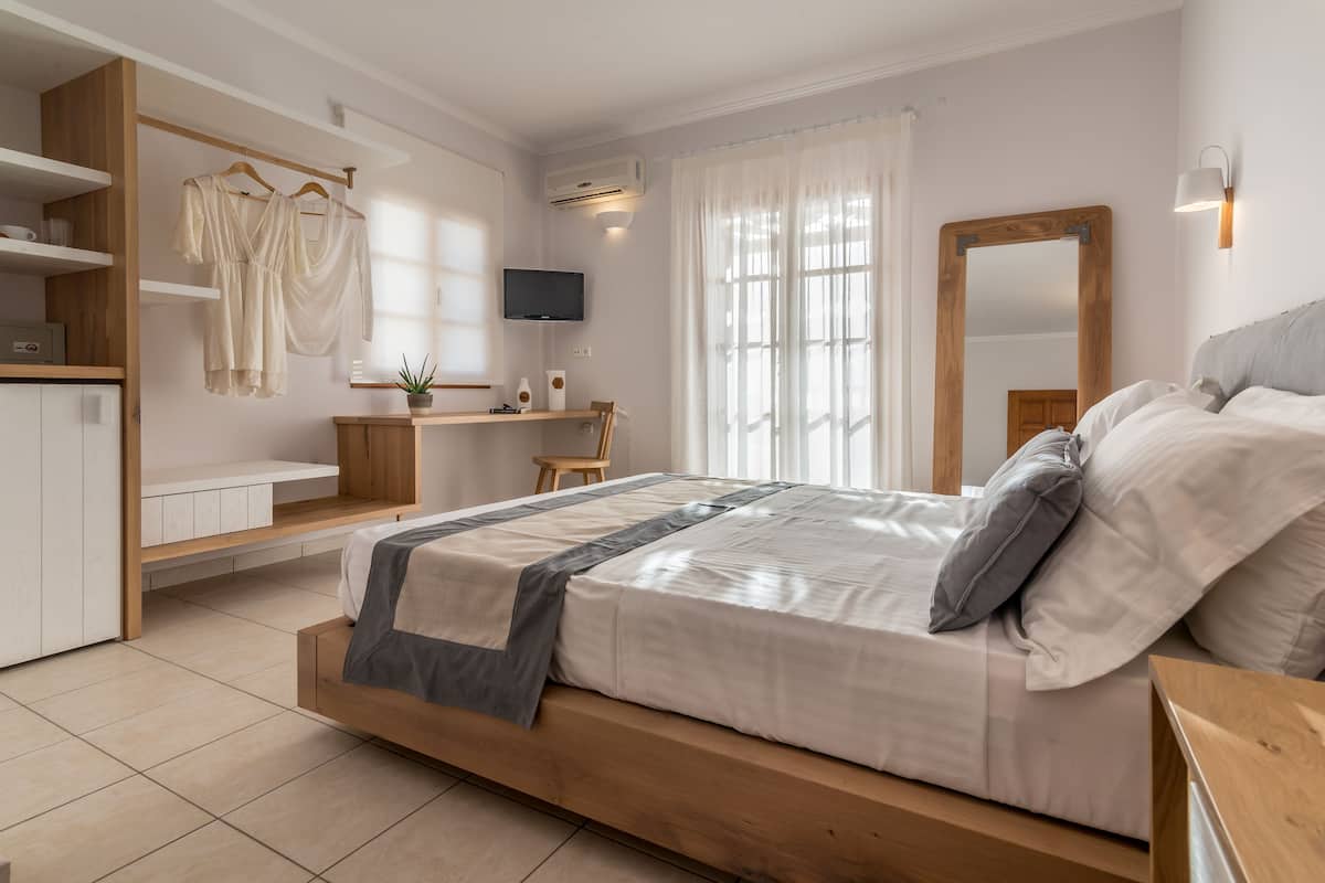 A modern bedroom with a wooden bed, a desk, and a TV.