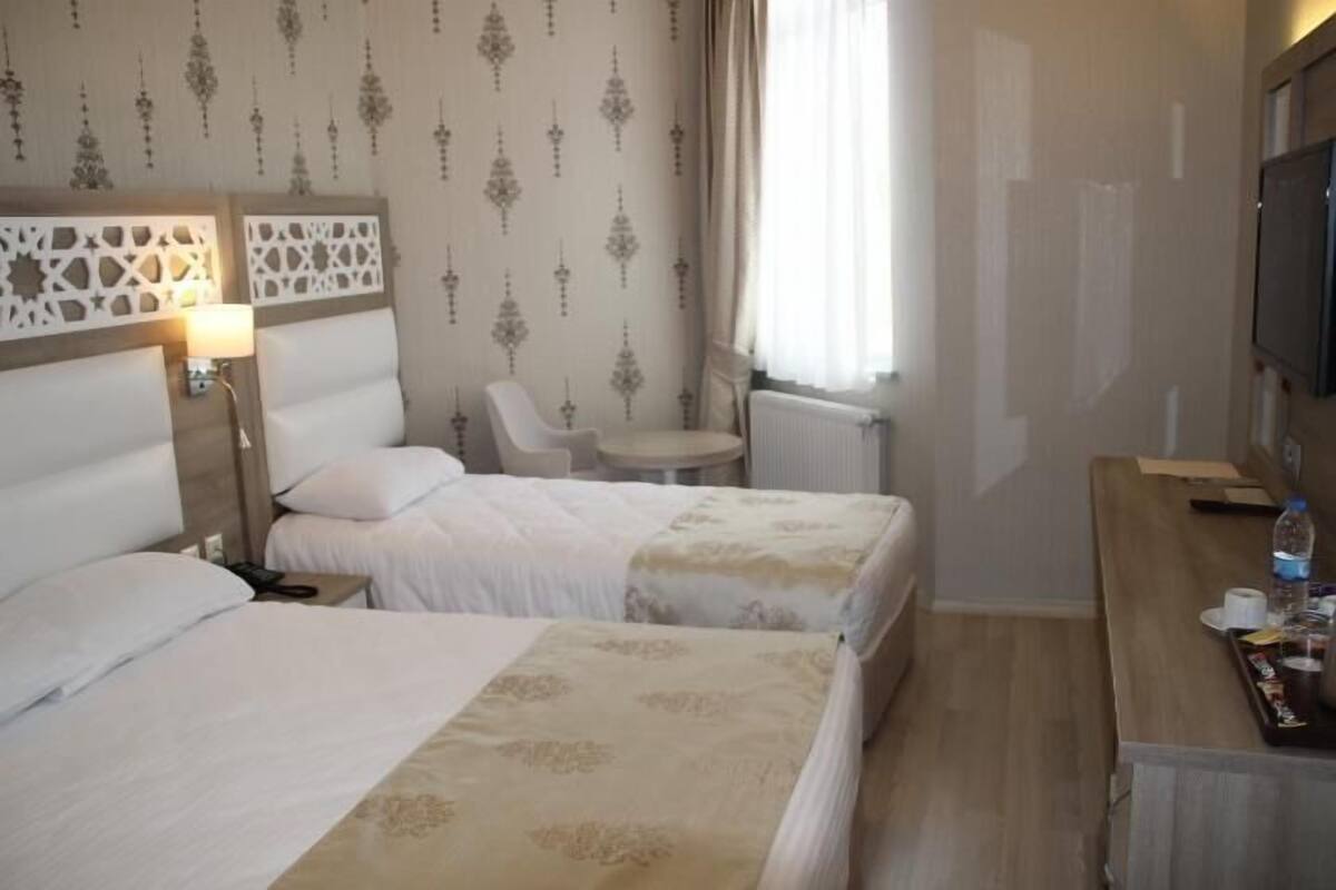 Een hotelkamer met twee bedden, een tafeltje, een stoel, een televisie en een radiator.