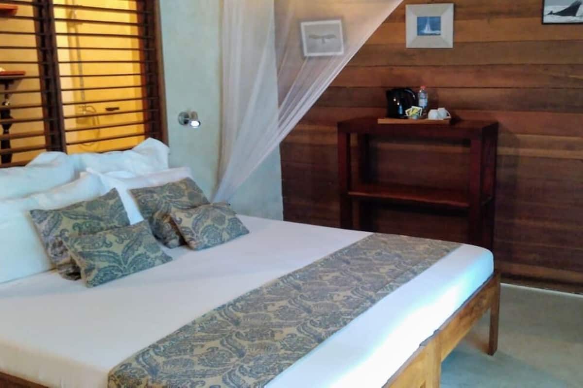 Ein Schlafzimmer mit Bett, Nachttisch, Sessel und Fernseher.