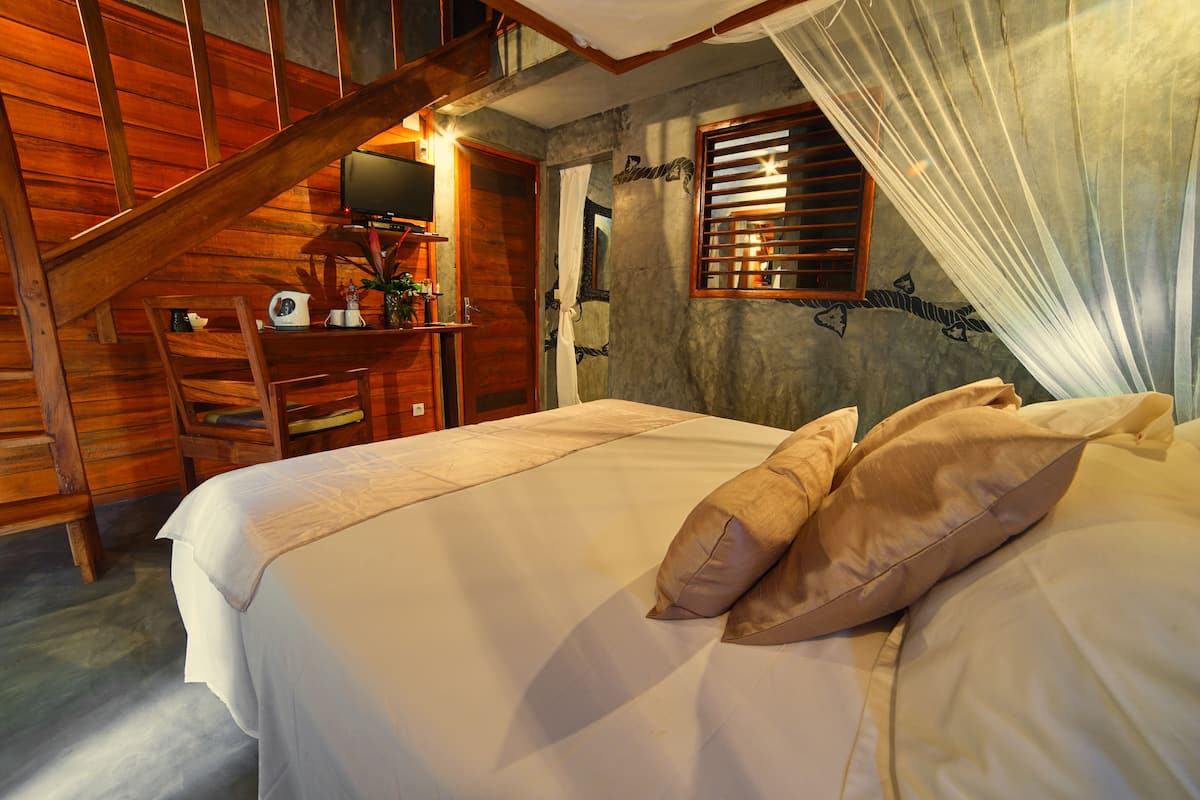 Ein Schlafzimmer mit einer Holztreppe, einem Bett mit weißer Bettwäsche und einem Schreibtisch mit einer Pflanze.