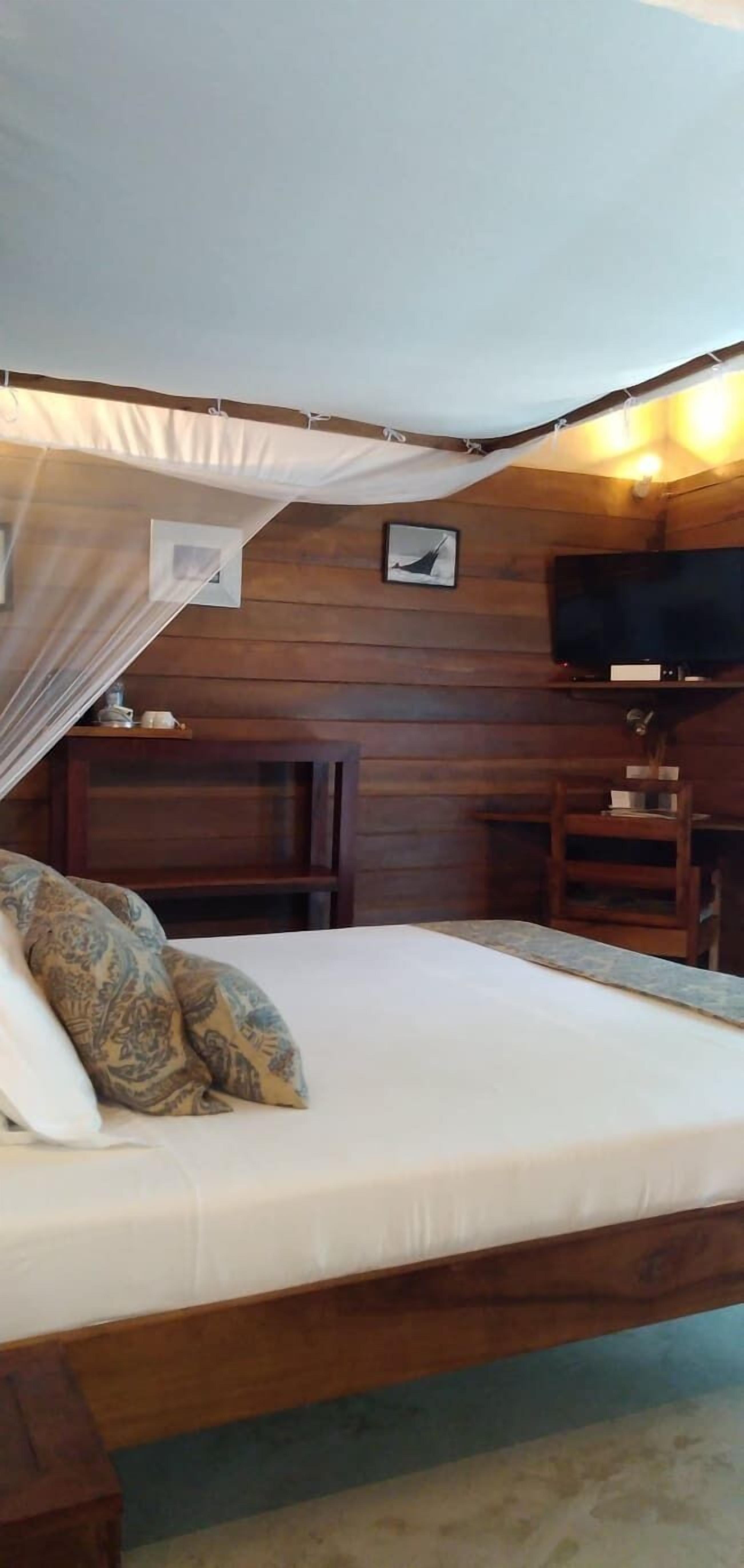 Una habitación de madera con una cama, un televisor y una mesita.