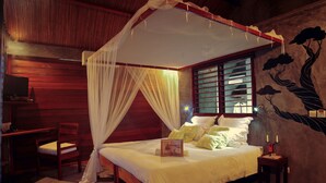 Un dormitorio con cama con dosel, una mesita de noche con velas y un mural en la pared.