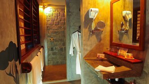 Un baño con pared de piedra, tocador de madera, espejo, secador de pelo y toallero.