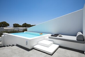 Ett poolområde på taket med en bubbelpool, sittplatser och trappor.