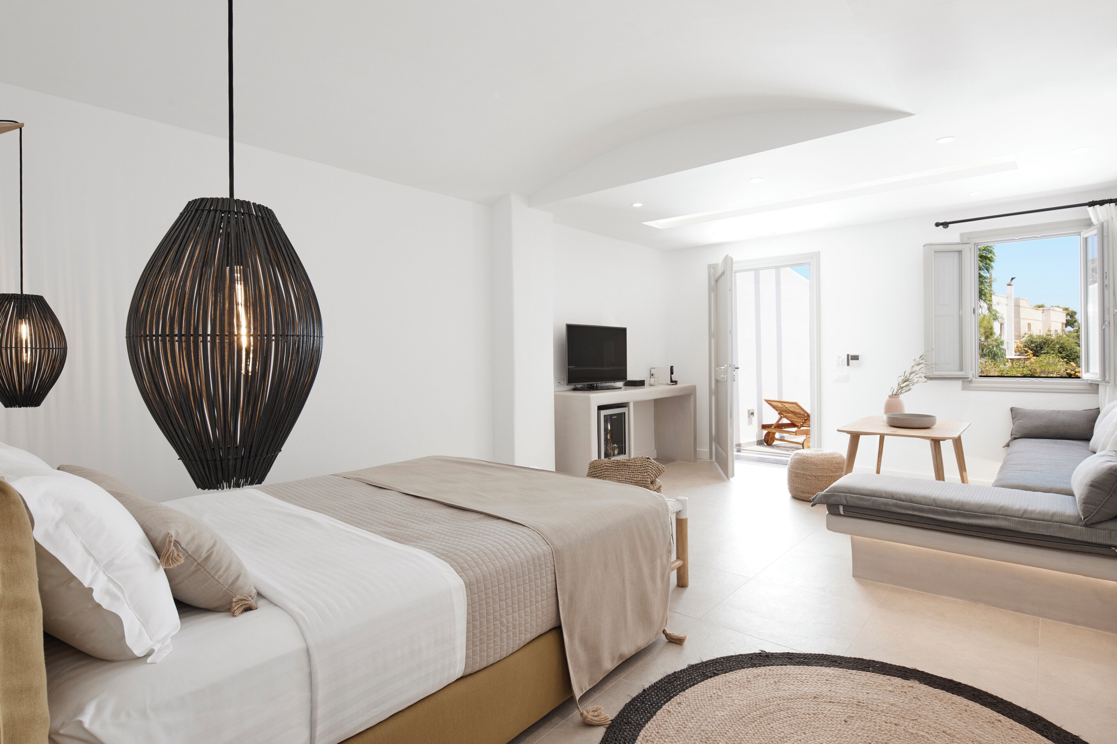 Un dormitorio moderno con cama, sofá, televisor y ventana con vistas.