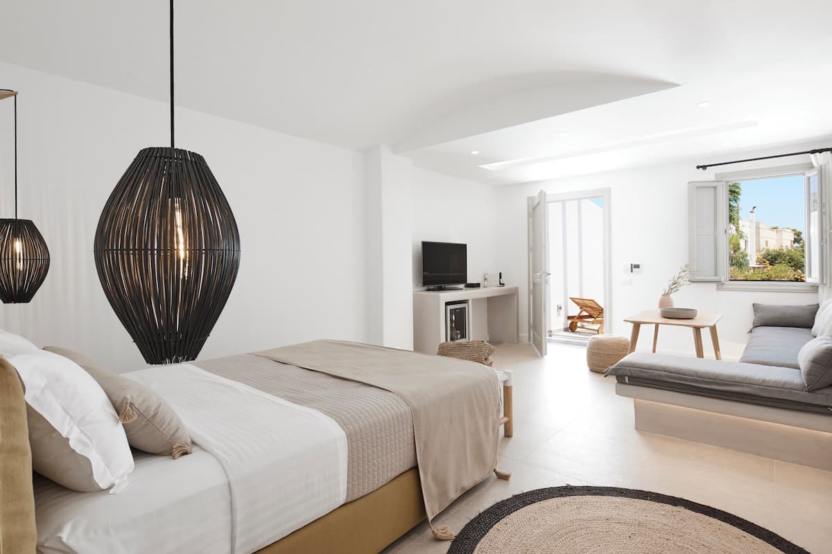 A modern bedroom with a bed, a sofa, a TV, and a window with a view.