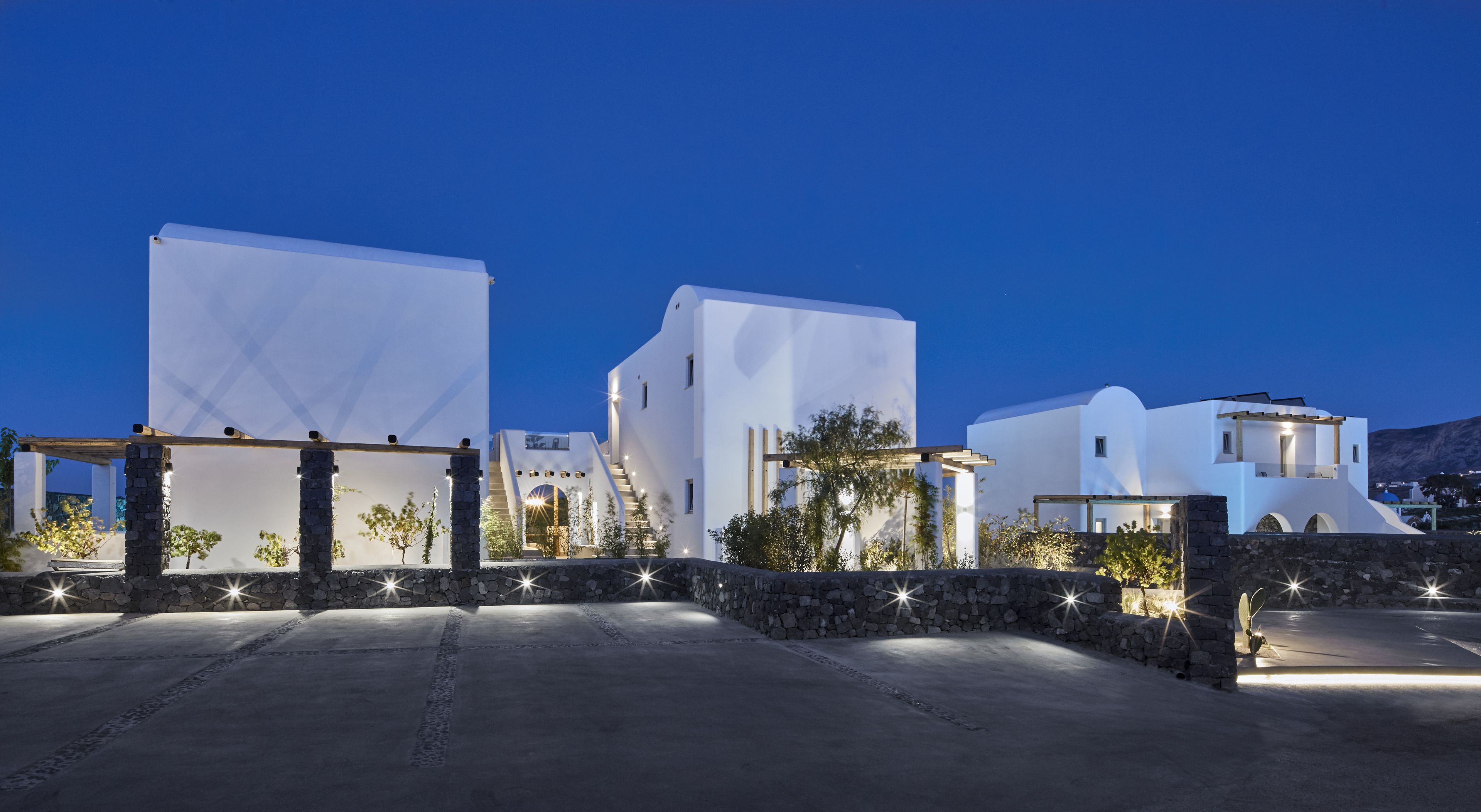 A modern white building with a stone pathway and a small garden area.
