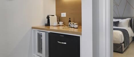 A compact kitchen with white cabinetry, a built-in dishwasher, and a countertop with a coffee maker and a small appliance.