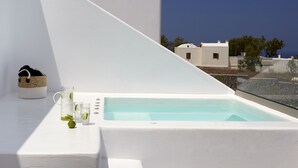 Una piscina infinita blanca amb una vista despejada del mar i edificis al fons.