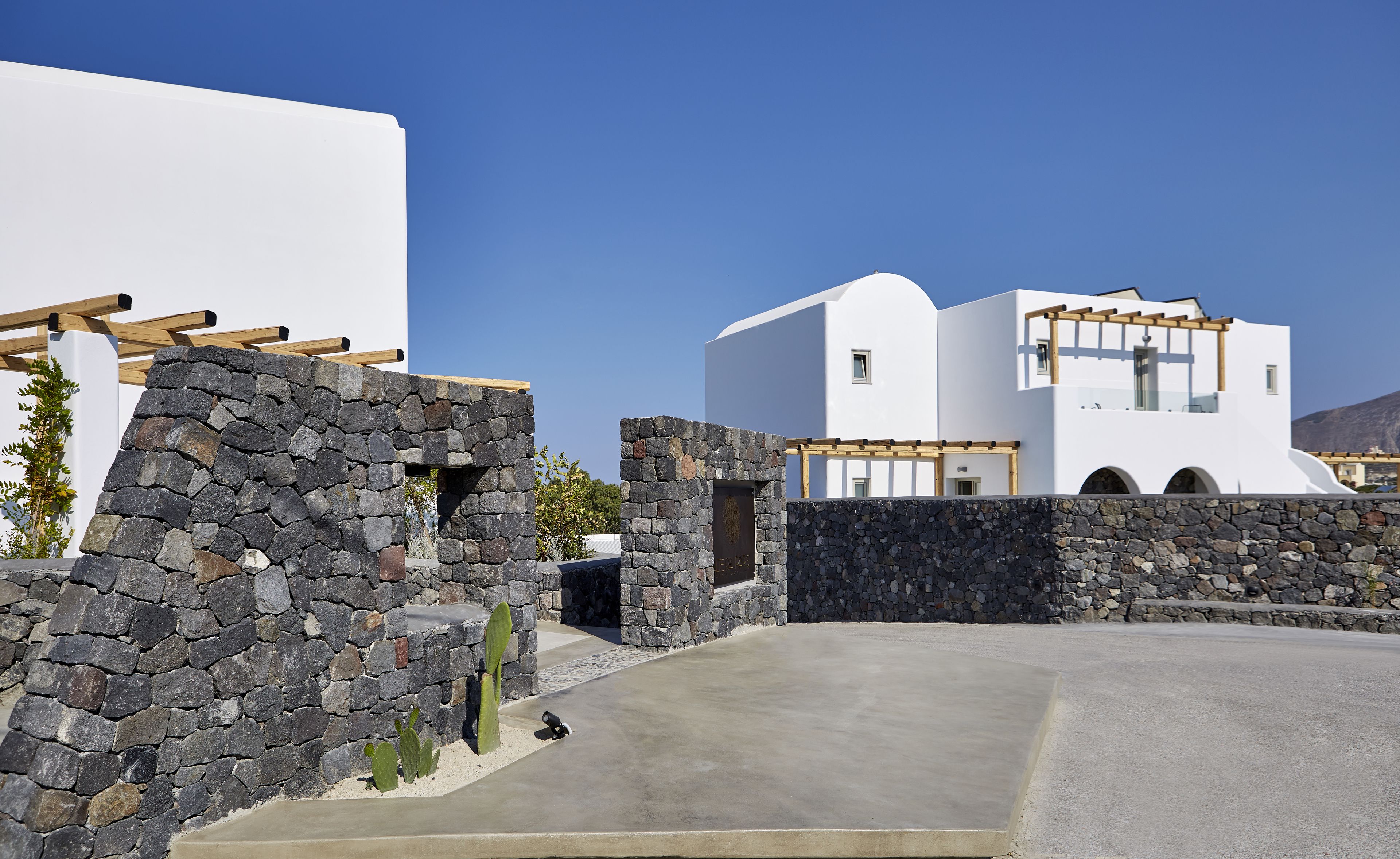 A modern white building with stone walls and a concrete driveway.