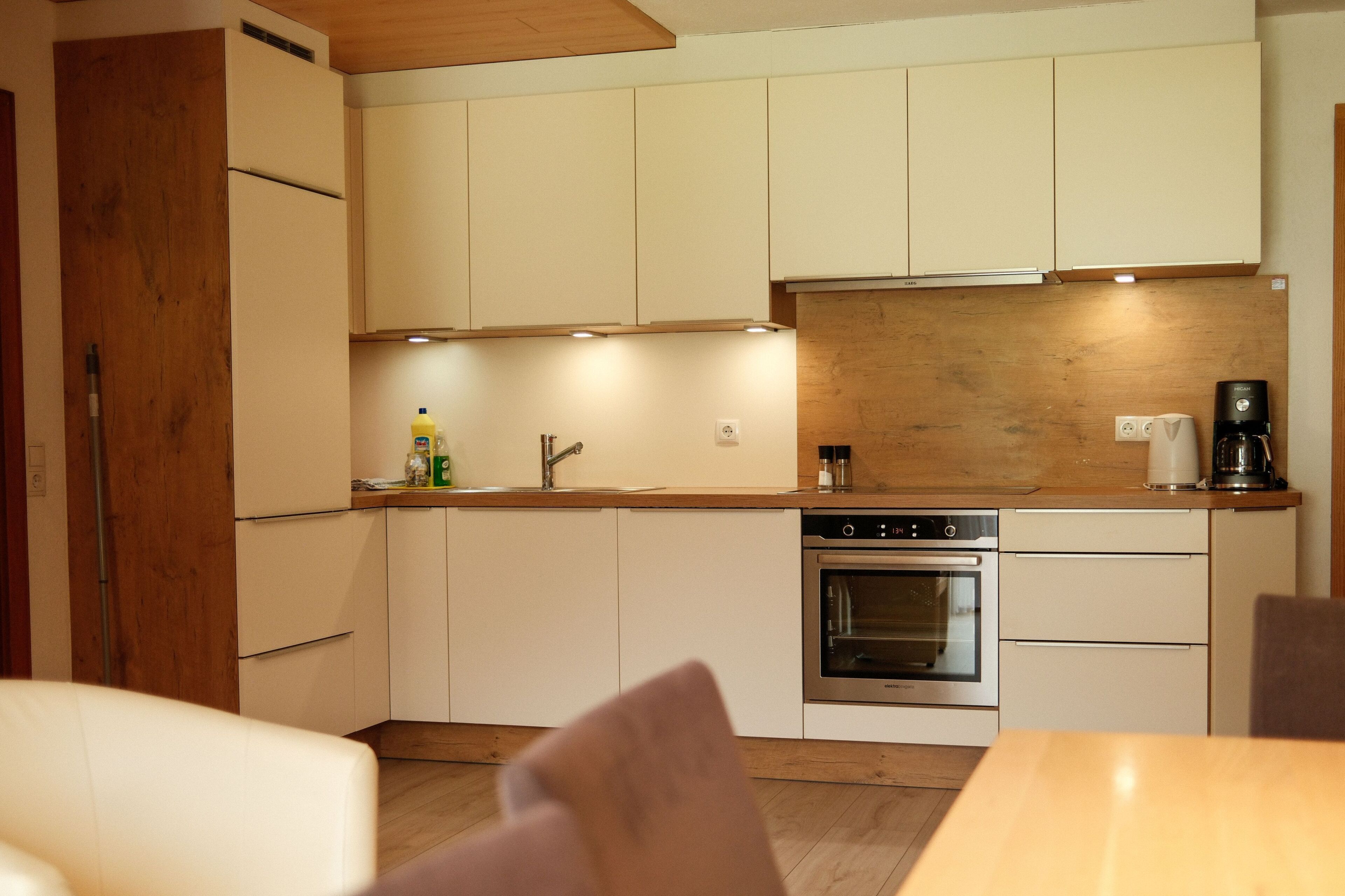 A modern kitchen with wooden cabinets, a built-in oven, and a coffee maker.