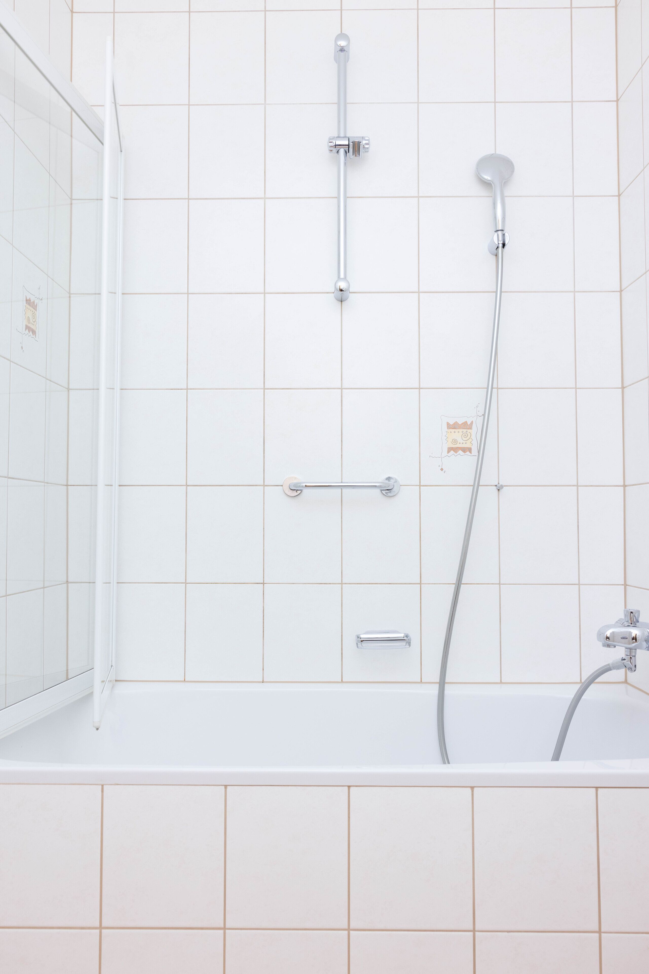 Une salle de bain moderne équipée d’une baignoire, d’une douche et d’un pommeau de douche à main.