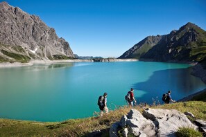 A group of hikers near a turquoise lake surrounded by mountains. - Kella-Egg (Brand)
