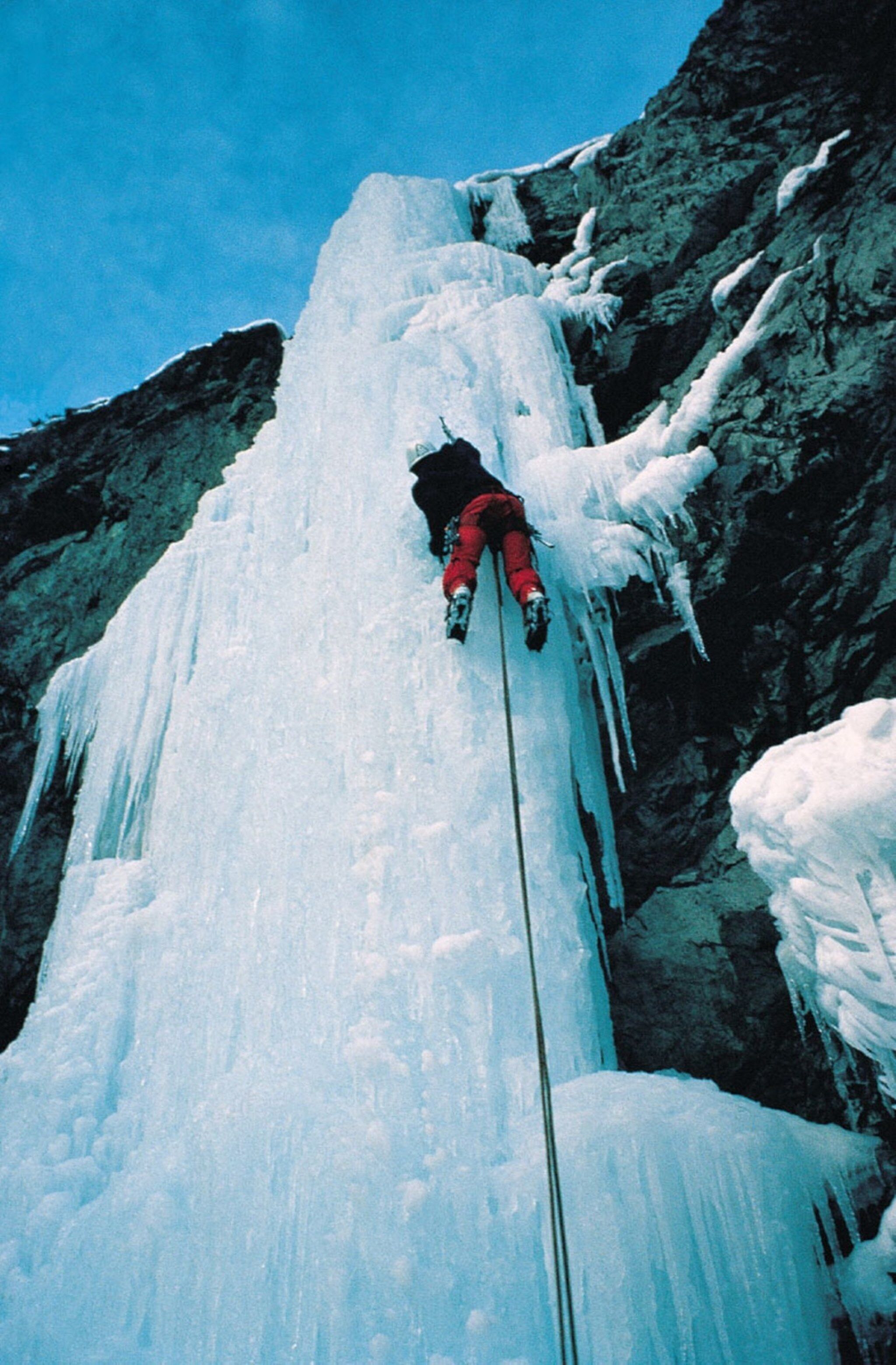 A person climbing a large ice formation.