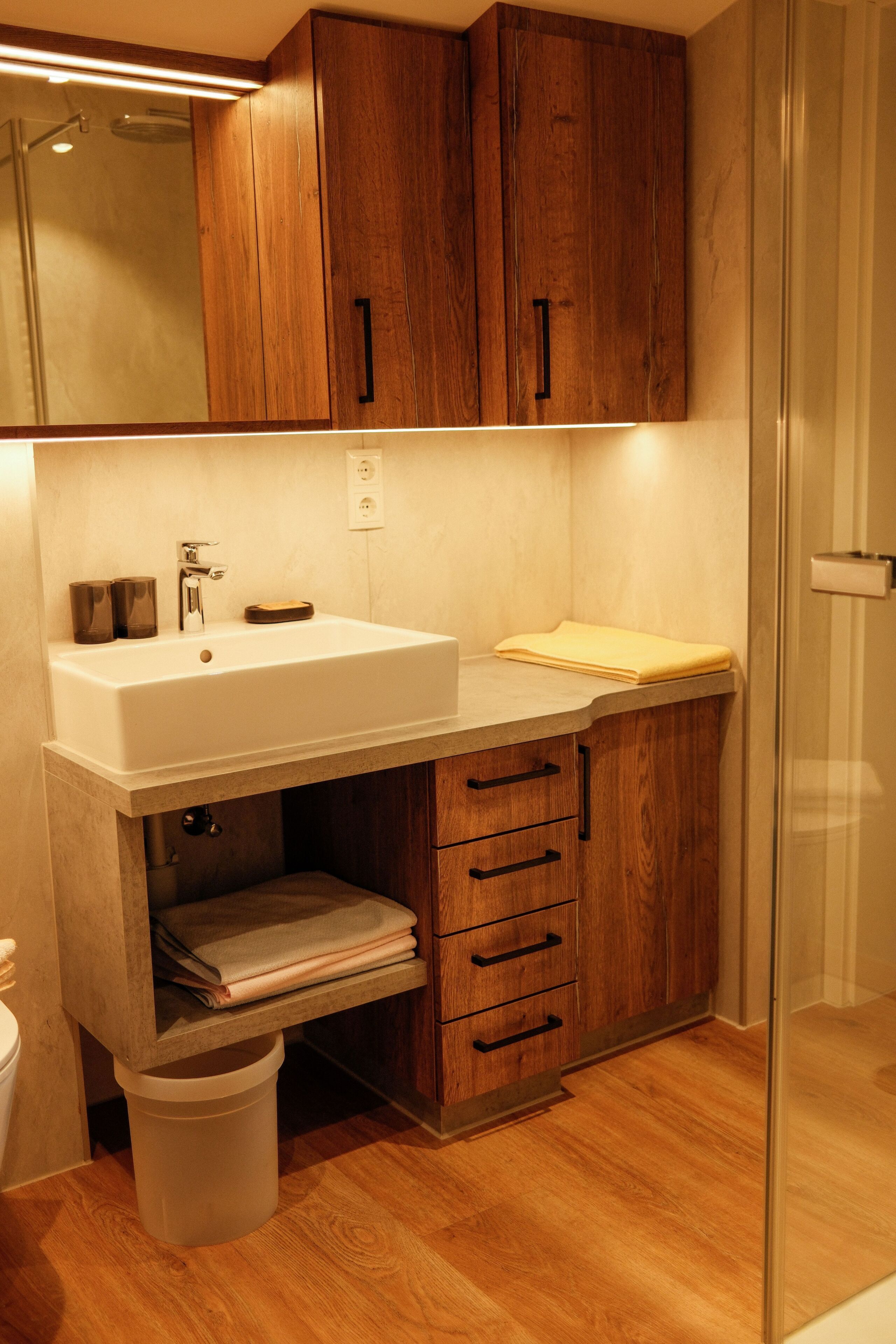 Un bagno con mobili in legno, un lavandino bianco e uno specchio sopra.