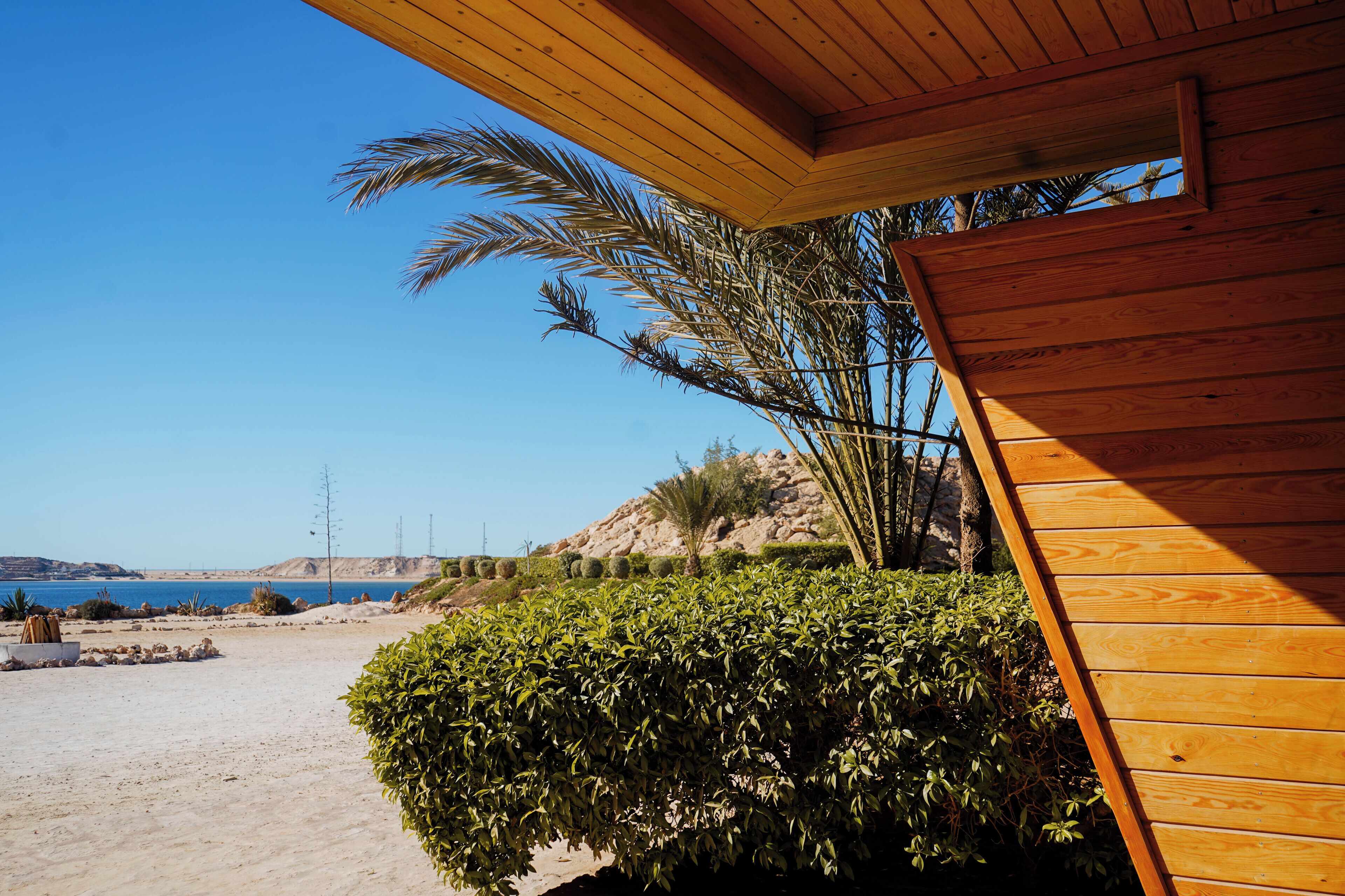 Ein Holzhaus mit Blick auf einen Strand und einen klaren Himmel.