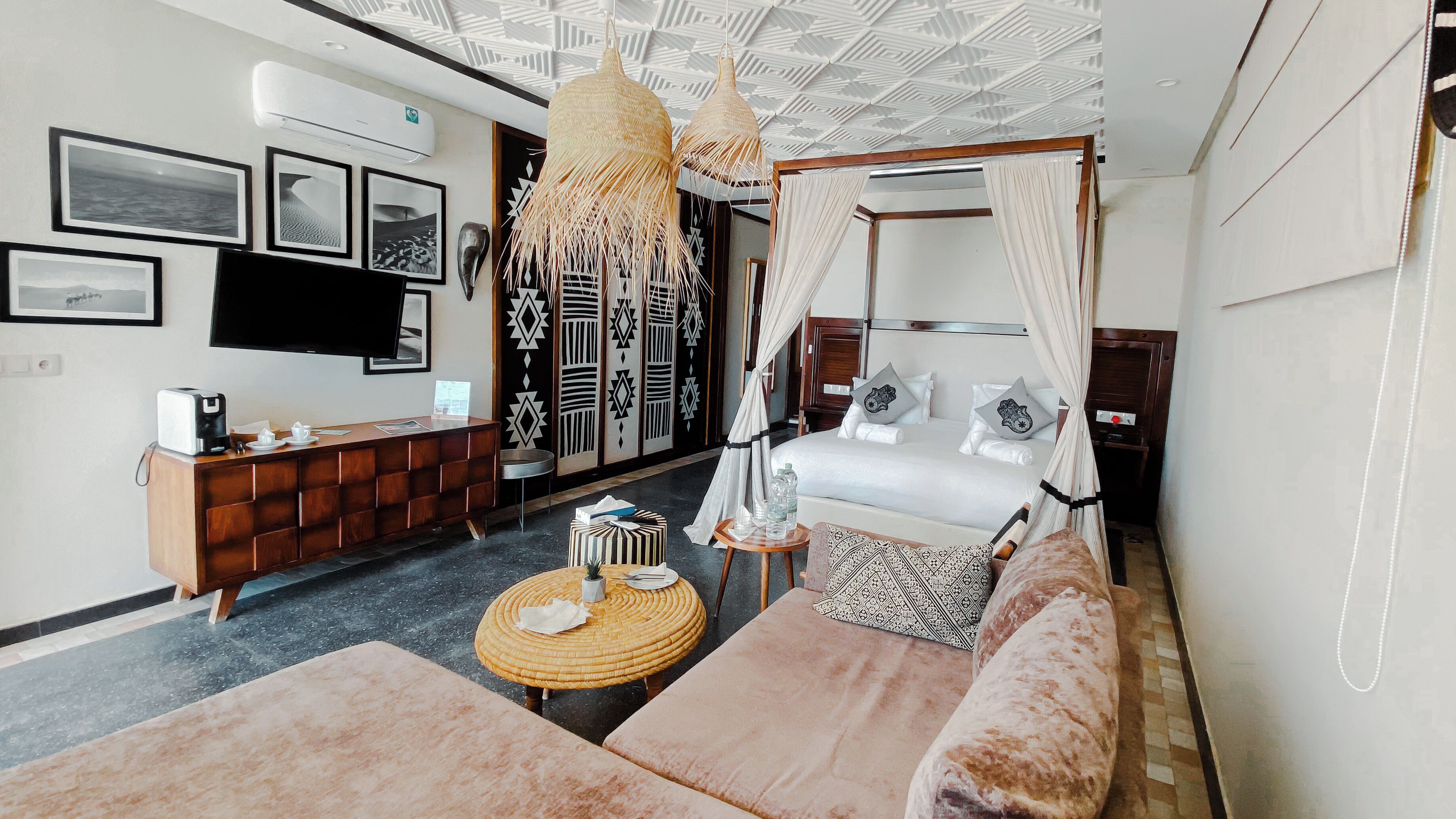 Una habitación de hotel moderna con una cama, un sofá, una mesita y un televisor.