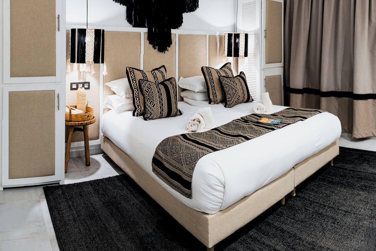 Un cuarto de hotel moderno con una cama grande, una mesita auxiliar y vista a la ciudad.