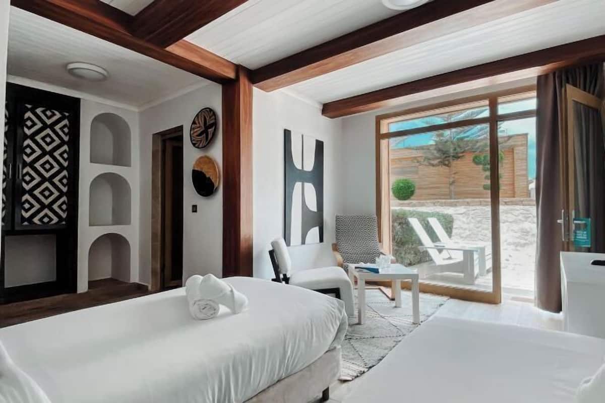 Una habitación de hotel con cama, una silla, una mesita y vistas al exterior.