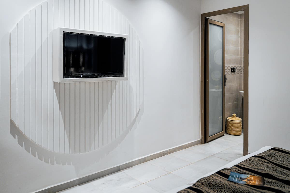 Una habitación con un ventanal grande, una puerta con panel de vidrio y piso de baldosas.