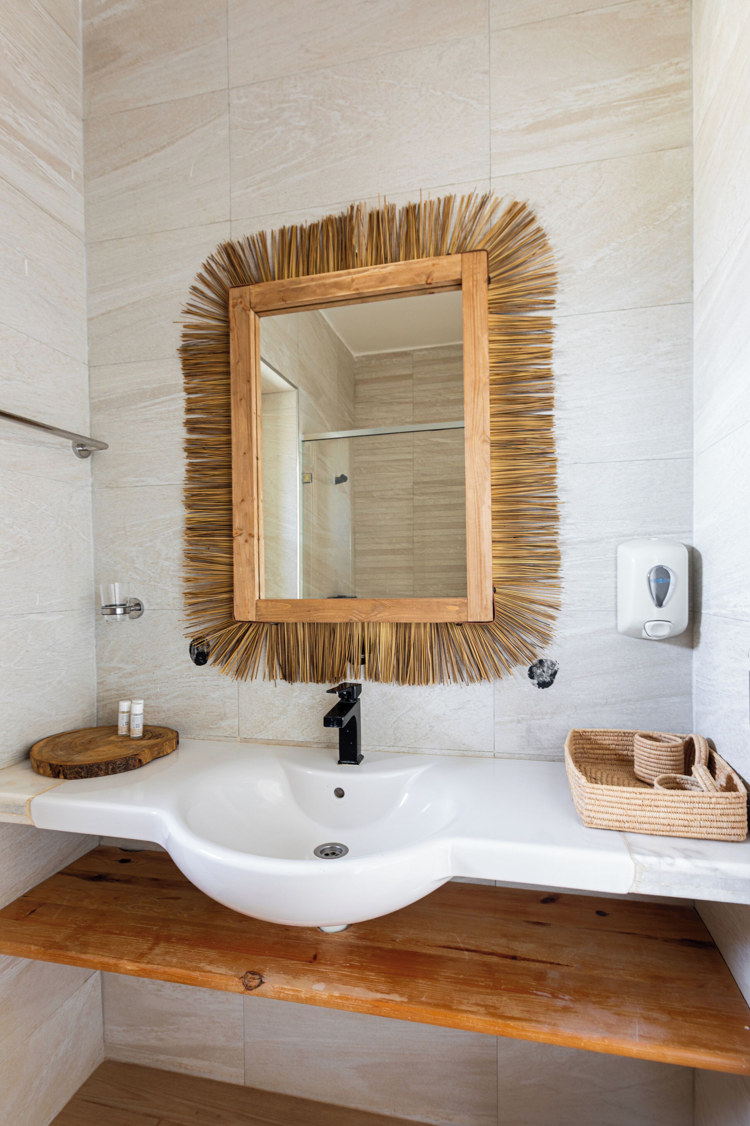 A bathroom with a white sink, wooden-framed mirror, and a towel rack.