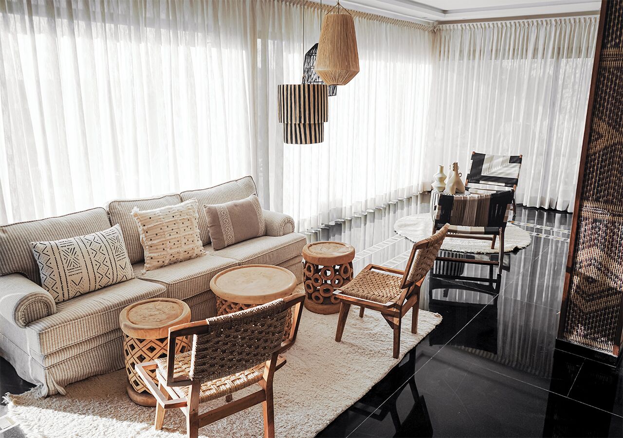 Un salon comprenant un canapé, deux fauteuils, une table basse et une table à manger avec des chaises.