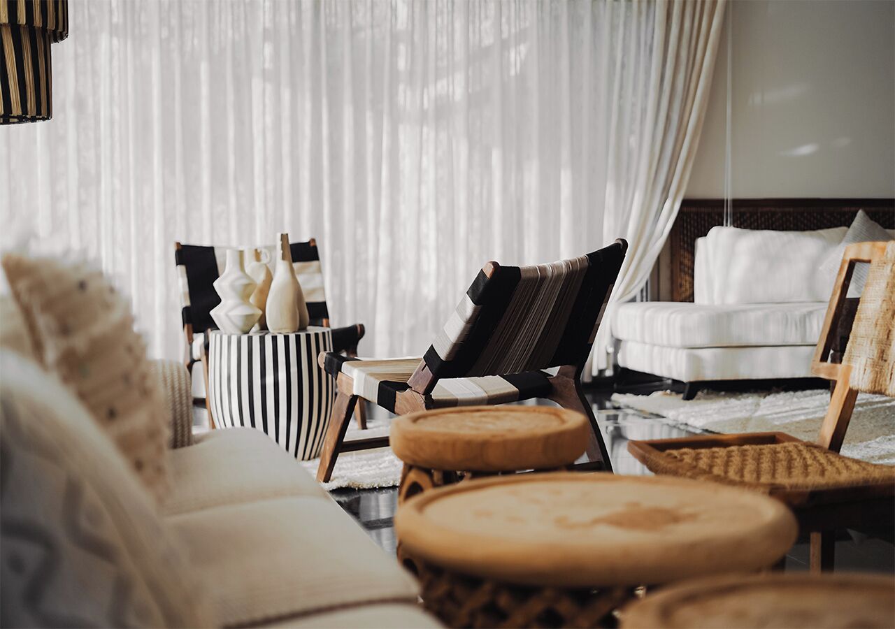 Una habitación acogedora con sofá, sillón y cama. Hay taburetes de madera y una mesita con adornos.