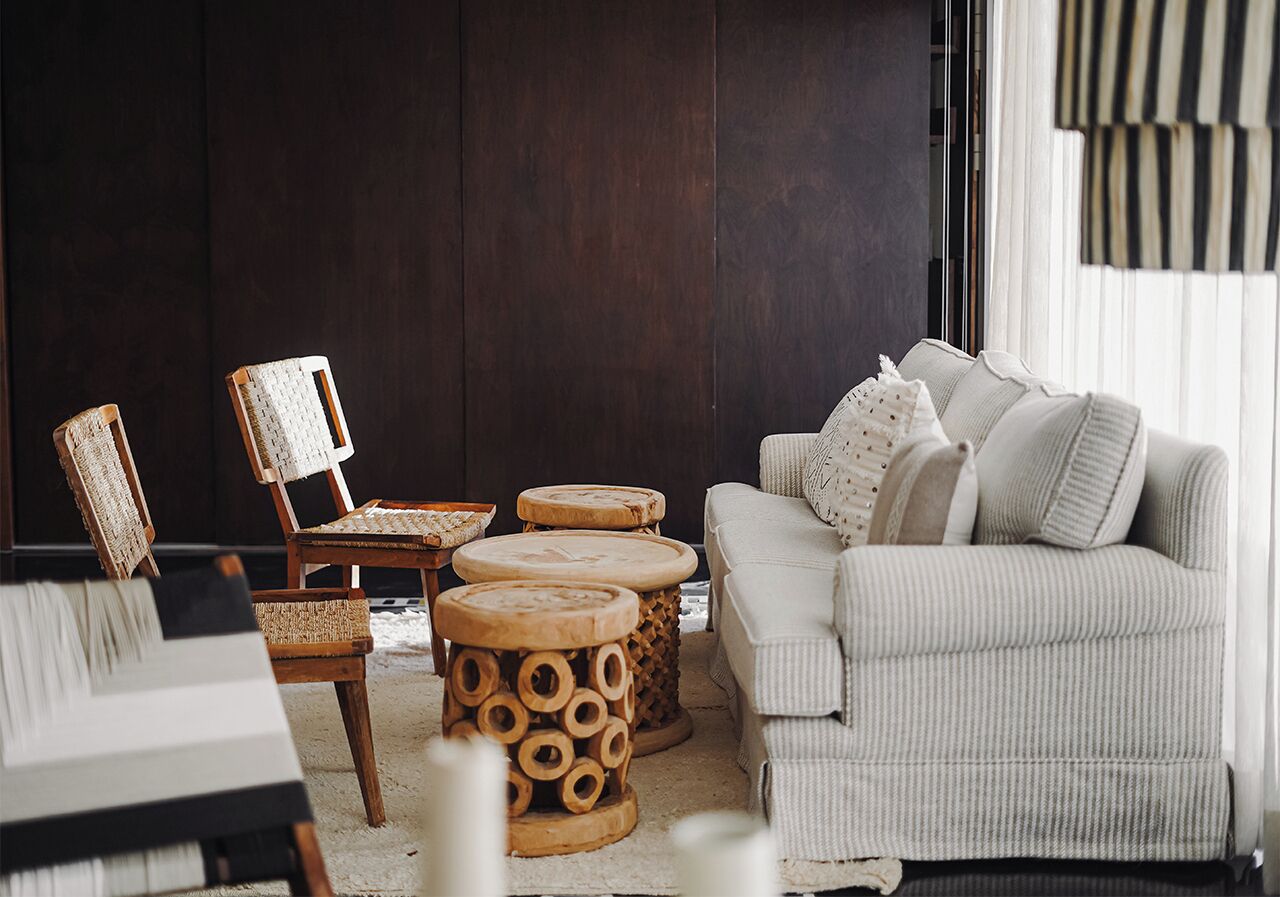 A living room with a sofa, two chairs, and three round wooden side tables.