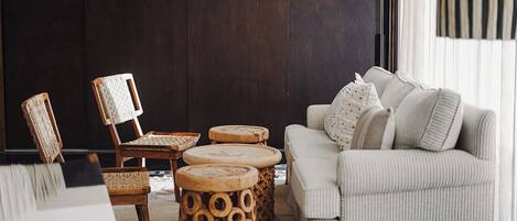 A living room with a sofa, two chairs, and three round wooden side tables.