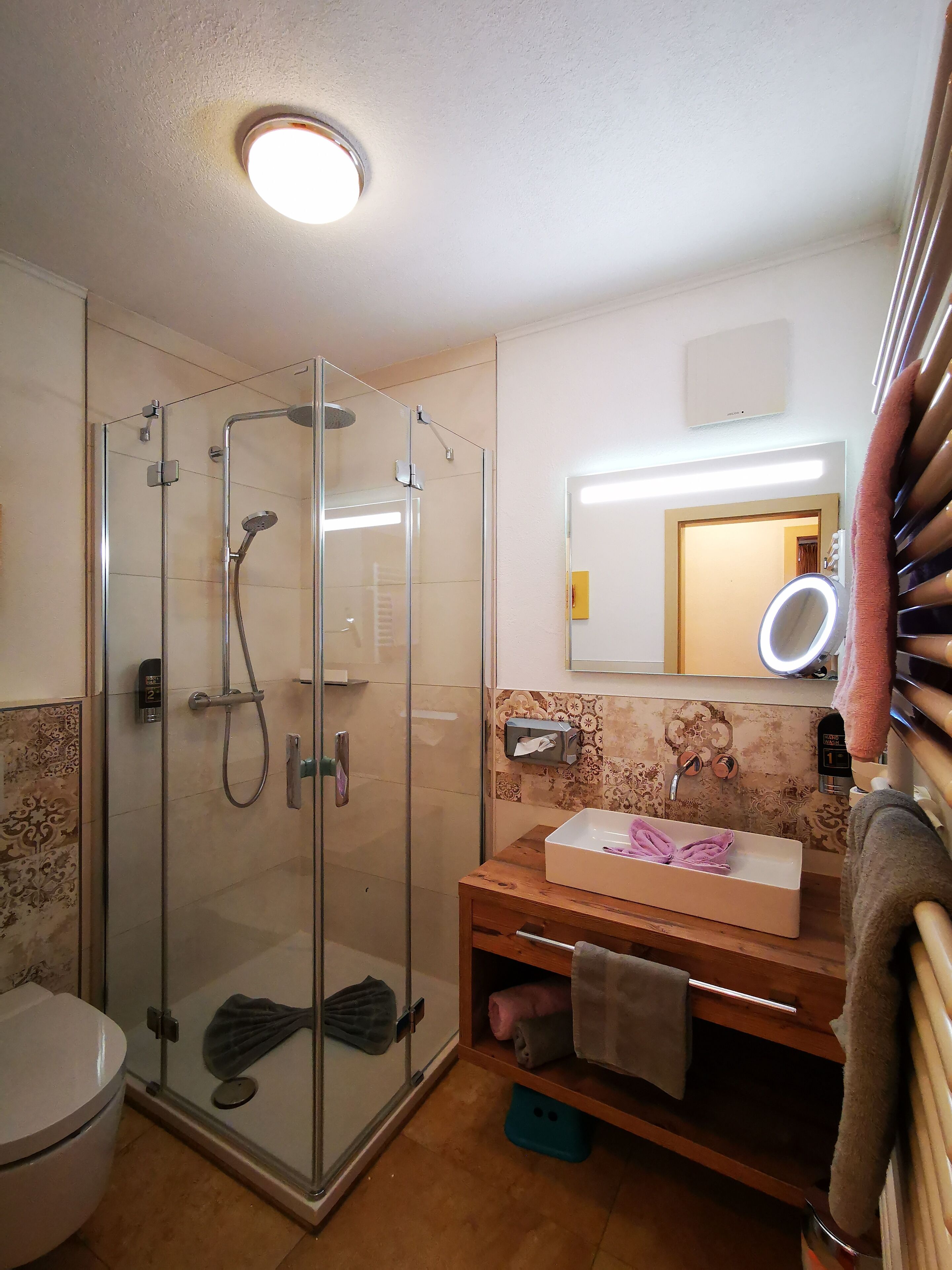 A bathroom with a glass-enclosed shower, a sink with a mirror, and a toilet.