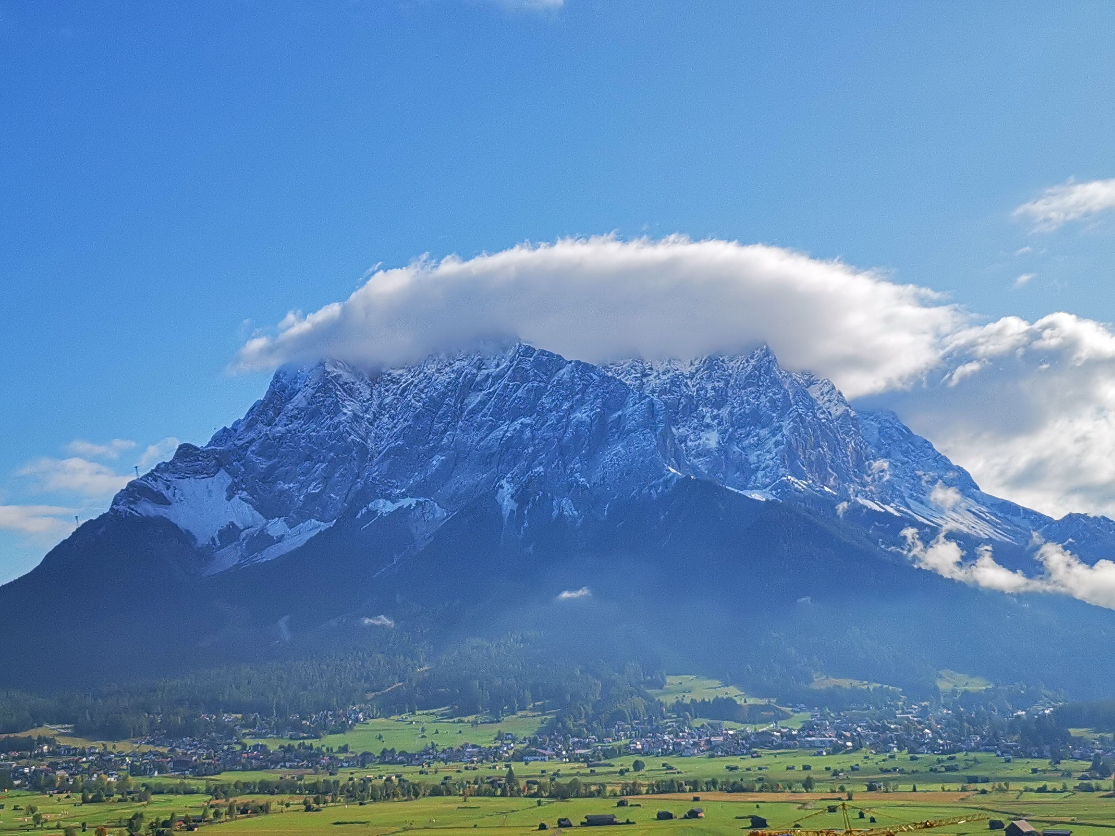 Une montagne dont le sommet est enneigé, avec une ville située à ses pieds.