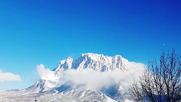 A snow-covered mountain with a clear sky and a small building with a tower in the foreground.