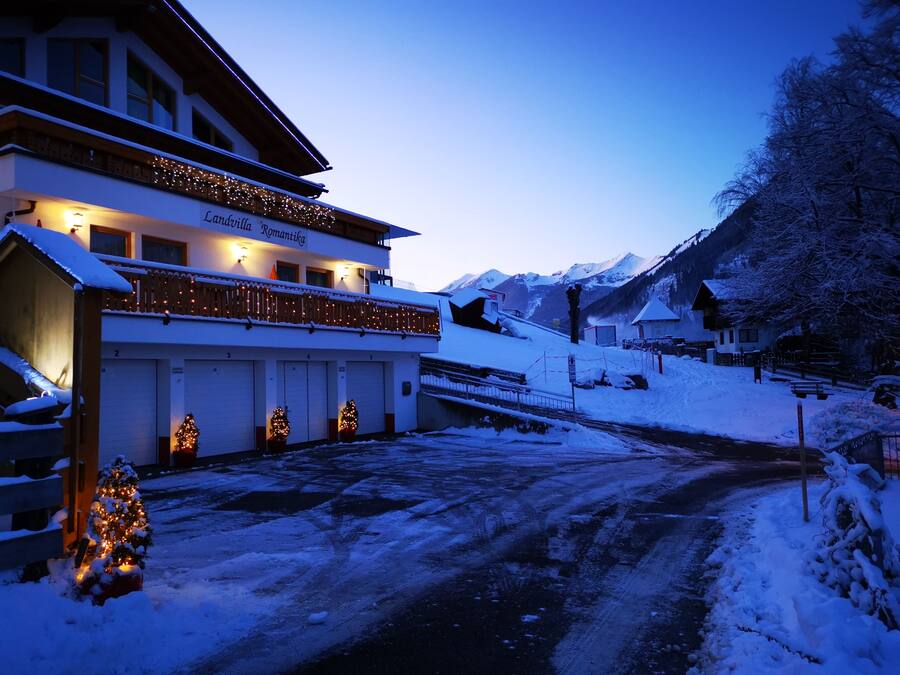 Un hotel con balcón, varias puertas de garaje y un paisaje cubierto de nieve.
