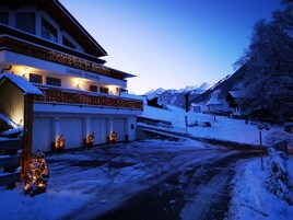 Un hotel con balcón, varias puertas de garaje y un paisaje cubierto de nieve.