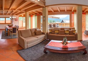 Amplia sala de estar con techo de madera, un sofá, una mesa de centro y un comedor con sillas y una mesa.