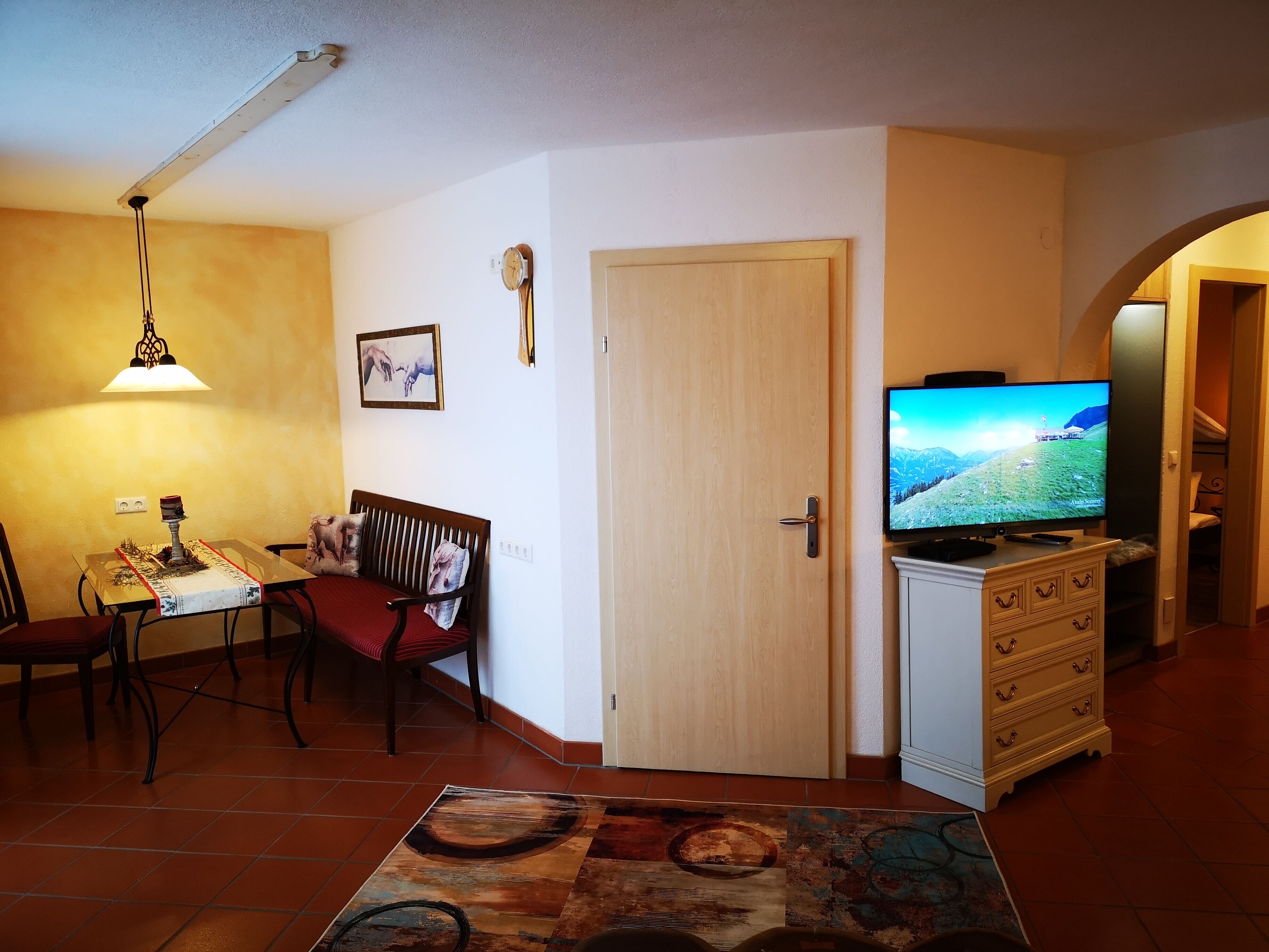 Ein gemütliches Wohnzimmer mit Essbereich, einem Fernseher und einer Tür zu einem anderen Raum.