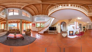 A spacious living area with a high ceiling, wooden beams, a fireplace, and a TV. - Landvilla Romantika (Lermoos)