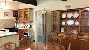 A traditional kitchen with wooden cabinets, a dining table, and a variety of kitchenware. - Hewenden Mill Holiday Homes (Bradford)