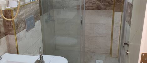 A modern bathroom with a glass-enclosed shower, a white sink, and a toilet.