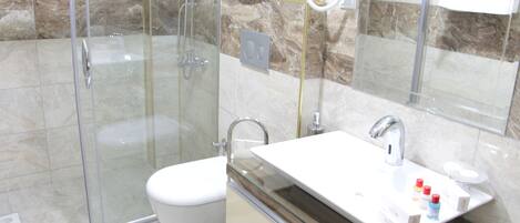 Un baño moderno con cabina de ducha de vidrio, inodoro blanco y tocador con espejo.
