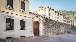 A historic building with a large wooden door and ornate window frames, adjacent to a stone wall. - Porta Torre Lofts (Como)