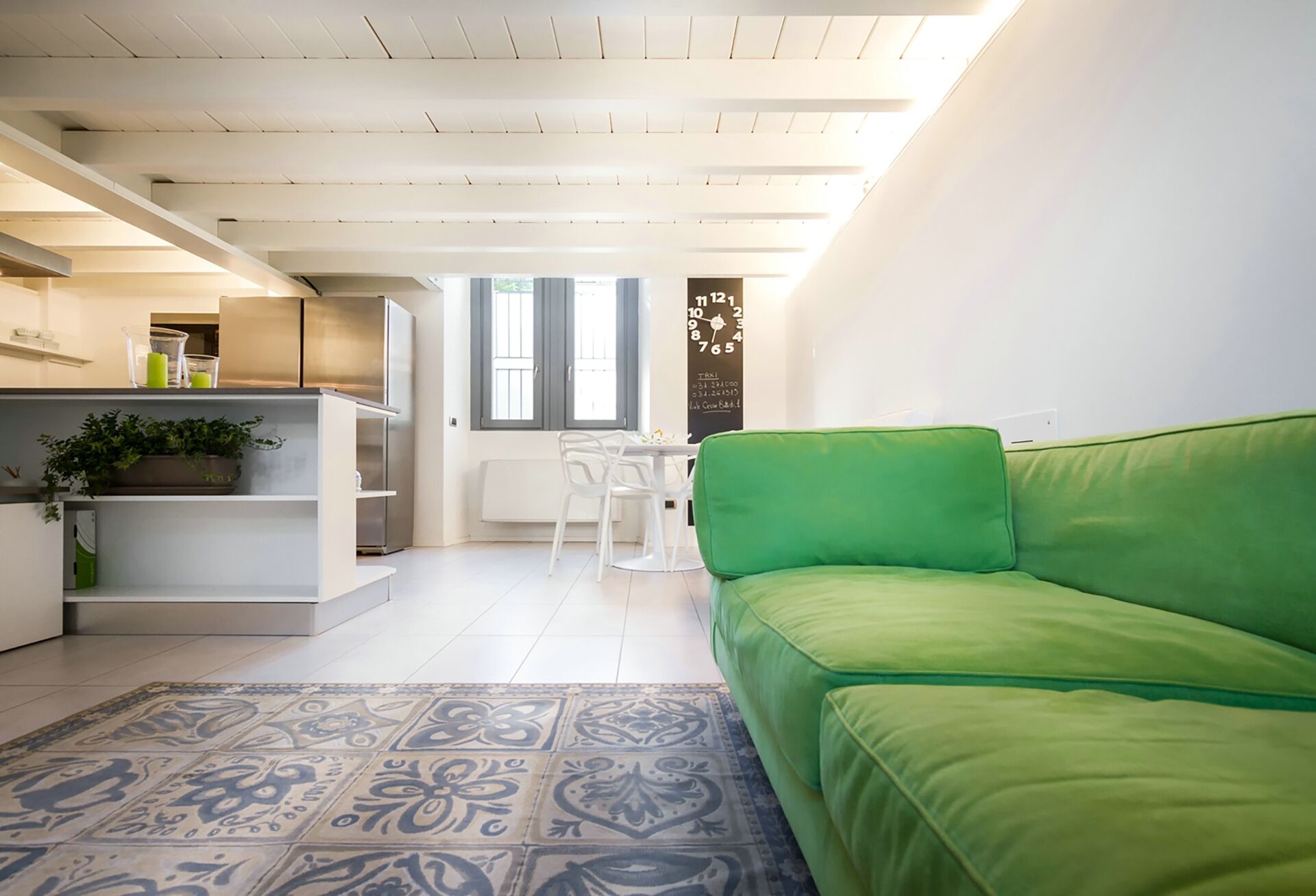 Un espace de vie moderne comprenant un canapé vert, un coin cuisine et une table à manger.